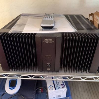 Sale Photo Thumbnail #148: Rotel RMB-1075 five-channel power amplifier with THX certification, featuring a black finish with prominent heat sink fins, complete with a remote control and manual.