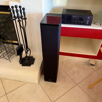Sale Photo Thumbnail #280: Definitive Technology floor-standing tower speaker with a glossy top cap, shown alongside a vintage Sansui stereo receiver and a black wrought iron fireplace tool set.