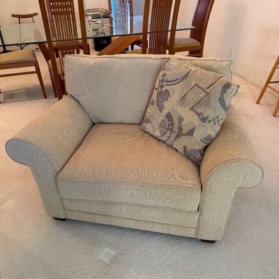 Sale Photo Thumbnail #306: Contemporary oversized armchair in beige textured upholstery with rolled arms, accompanied by a patterned accent pillow.