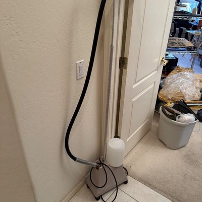 Jiffy Steamer professional garment steamer with a flexible hose, metal rod, and plastic water bottle, showing some signs of use.