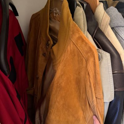 Sale Photo Thumbnail #172: Vintage mustard-yellow suede bomber jacket with a ribbed knit collar, hanging in a closet alongside other outerwear.