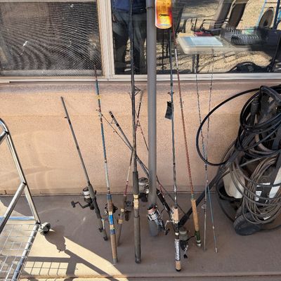Sale Photo Thumbnail #235: Assortment of vintage and modern fishing rods with spinning reels, including a Shimano Sienna rod and a grey protective rod tube.