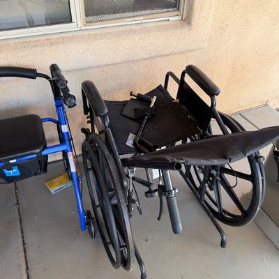 Sale Photo Thumbnail #247: Black folding wheelchair with hand brakes, shown alongside a blue rolling walker with a padded seat.