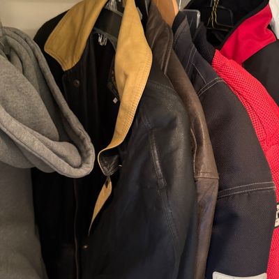 Sale Photo Thumbnail #178: Assorted men's outerwear hanging in a closet, including a black leather jacket with a tan collar, a brown leather jacket, and a Firstgear motorcycle jacket.