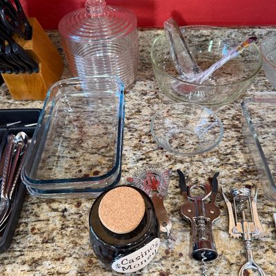 Sale Photo Thumbnail #224: Assorted kitchenware and bar tools, including Pyrex baking dishes, glass mixing bowls, a lidded glass jar, corkscrews, and a small ceramic jar labeled "Casino Money."