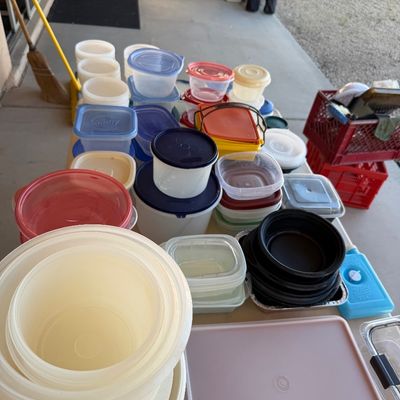 Sale Photo Thumbnail #234: Large assortment of vintage and modern plastic food storage containers, including Tupperware and Ziploc brands, displayed on an outdoor table.