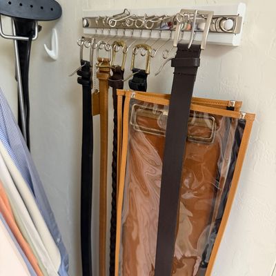 Sale Photo Thumbnail #115: Wall-mounted sliding belt rack holding an assortment of leather belts in black, brown, and tan.