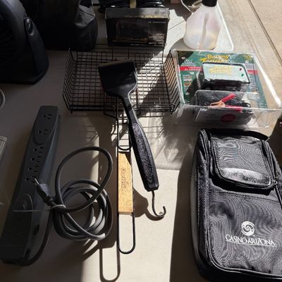 Sale Photo Thumbnail #109: Assortment of household and garage items, including a power strip, a Char-Broil grill brush, a wire basket, a Battery Tender in its packaging, and a Casino Arizona branded soft case.