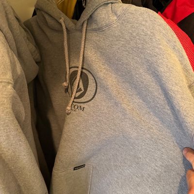 Sale Photo Thumbnail #181: Volcom heather gray pullover hoodie with a front graphic logo and drawstring hood, hanging in a closet.