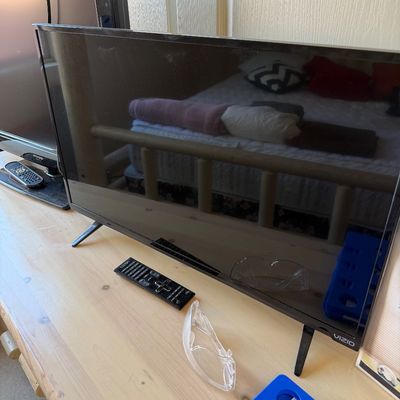 Sale Photo Thumbnail #194: Vizio flat-screen television with remote control, displayed on a light wood dresser.