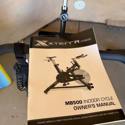 Sale Photo Thumbnail #230: Xterra Fitness MB500 indoor cycle owner's manual resting on the handlebars of the exercise bike.