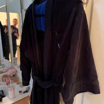 Sale Photo Thumbnail #167: Polo Ralph Lauren black terry cloth bathrobe with a blue lining and embroidered logo on the chest pocket, hanging on a bathroom door.