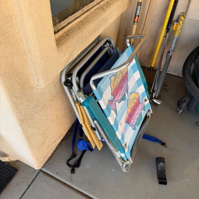 Sale Photo Thumbnail #255: Assorted folding beach chairs, including one with a colorful fish pattern, alongside garden tools and a golf club.