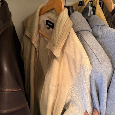 Sale Photo Thumbnail #173: Adolfo brand men's beige jacket with knit sleeves and collar, hanging in a closet alongside other outerwear.