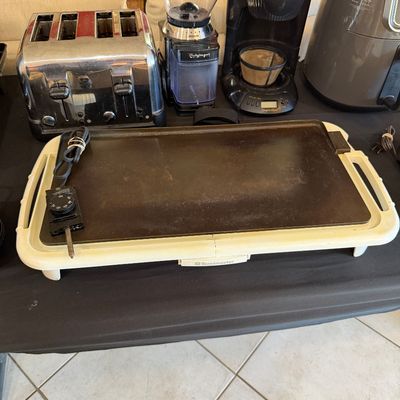 Sale Photo Thumbnail #260: Assorted kitchen appliances including a Toastmaster electric griddle, a four-slice chrome toaster, a Cuisinart coffee grinder, a West Bend coffee maker, and an air fryer.