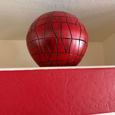 Sale Photo Thumbnail #285: Red decorative sphere with a black geometric web pattern, displayed on a shelf.