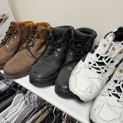 Sale Photo Thumbnail #120: Assorted men's footwear including brown and black leather work boots alongside white New Balance athletic sneakers, showing moderate wear.