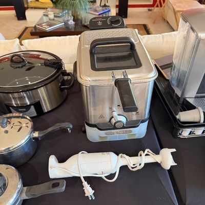 Sale Photo Thumbnail #262: Assorted kitchen appliances including a T-fal deep fryer, a Crock-Pot slow cooker, a white hand blender, and stainless steel pots.