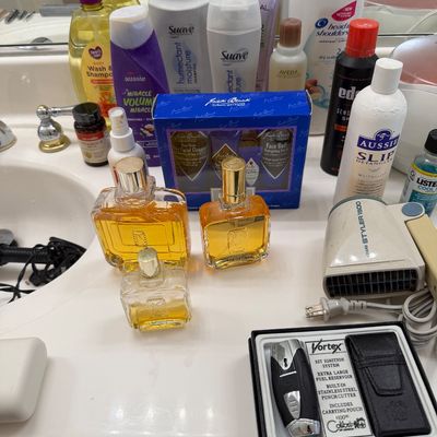 Sale Photo Thumbnail #135: Assortment of personal care items, including vintage cologne bottles, a Sears Styler 1500 hair dryer, a boxed Vortex lighter set, and various hair and body care products.