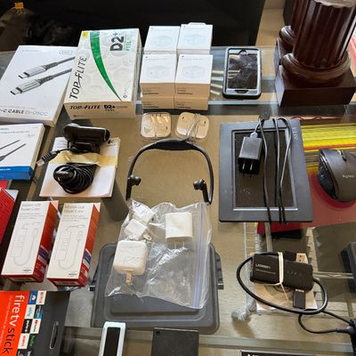 Assortment of electronics and accessories, including a Fire TV Stick 4K, Apple power adapters, a Logitech mouse, and various cables.