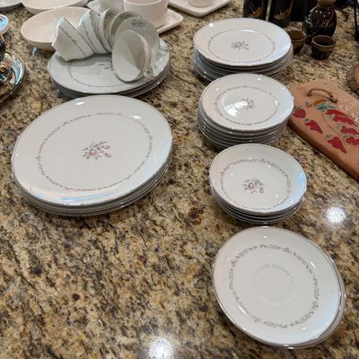 Sale Photo Thumbnail #204: Vintage fine china dinnerware set featuring a delicate pink rosebud pattern with silver trim, including dinner plates, salad plates, bowls, and teacups.