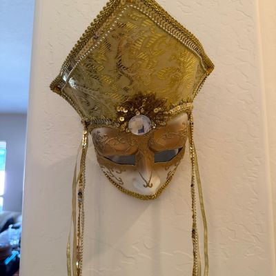 Ornate Venetian-style masquerade wall mask featuring a gold brocade headdress, sequin trim, and hanging ribbons.