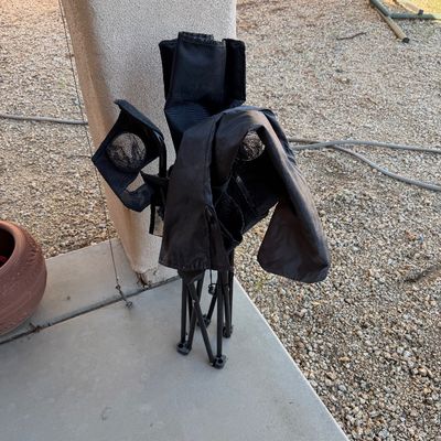 Sale Photo Thumbnail #245: Foldable black canvas camp chair with integrated cup holders, shown in its collapsed state.