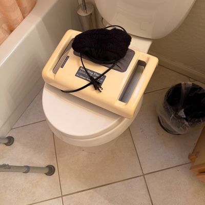 Sale Photo Thumbnail #162: Kneading Fingers Deluxe Model KS-99-01 portable massager with power cord and black fabric cover, resting on a toilet seat.