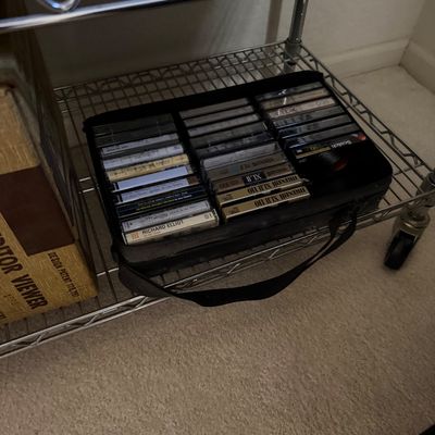 Vintage cassette tape collection in a black zippered carrying case, featuring Maxell XLII 110 and other blank and pre-recorded tapes.