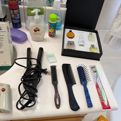 Sale Photo Thumbnail #147: Assorted personal care items including a Calvin Klein fragrance gift set, hair styling tools, combs, brushes, and various toiletries arranged on a bathroom vanity.