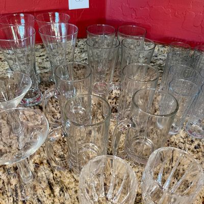 Sale Photo Thumbnail #210: Assorted glassware collection including heavy glass beer mugs, pilsner glasses, tumblers, and stemmed cocktail glasses.