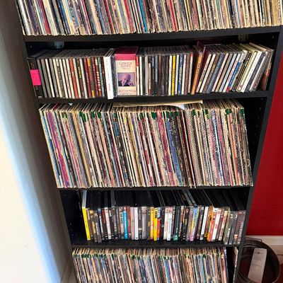 Sale Photo Thumbnail #292: Large collection of vinyl records, CDs, and DVDs organized on a black five-shelf bookcase.