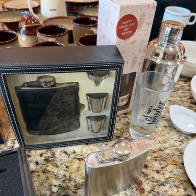 Sale Photo Thumbnail #199: Assorted barware including a boxed flask gift set with shot glasses and funnel, a stainless steel flask, an El Jimador shot glass, and a cocktail shaker.