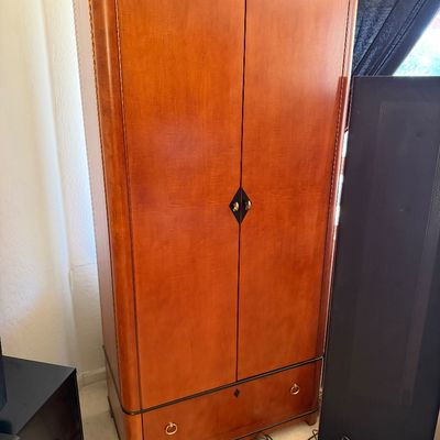 Sale Photo Thumbnail #145: Art Deco style cherry wood armoire featuring a black crown molding, two doors with diamond-shaped hardware, and a bottom drawer with brass ring pulls.