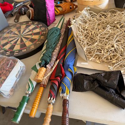 Assorted household and recreational items including vintage umbrellas with wooden handles, a dartboard, baseball gloves, and a box of...