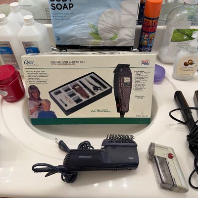 Sale Photo Thumbnail #136: Vintage Oster Deluxe Hair Clipper Set in its original box, displayed alongside a Braun hot air styler, a Remington shaver, and various household toiletries.
