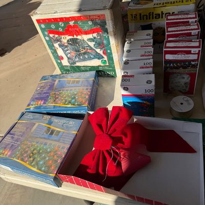 Assorted holiday decorations including a hand-painted cast iron tree stand, net light sets, GE light strings, light holders, and a large...