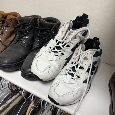 Sale Photo Thumbnail #122: Assorted men's footwear, including a pair of white New Balance athletic sneakers and black leather work boots, showing moderate wear.