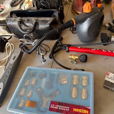 Assorted household and utility items, including a Nelson 24-piece brass accessory kit, a handheld steam cleaner, a red bicycle pump, and...