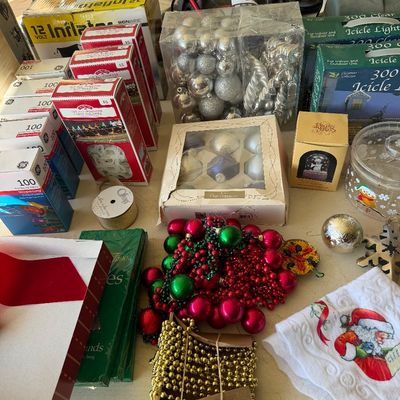 Assortment of vintage and modern Christmas decorations, including boxed ornaments, icicle lights, beaded garland, and a Santa Claus hand...