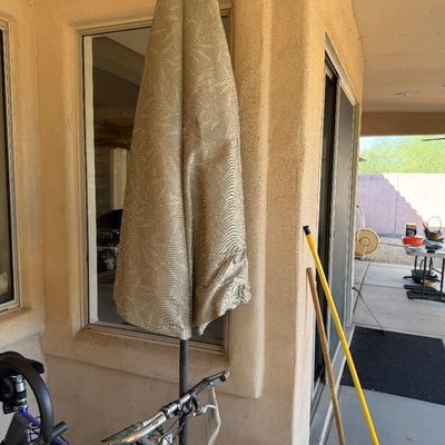 Sale Photo Thumbnail #221: Large outdoor patio umbrella with a textured beige fabric canopy, shown closed on a metal pole.