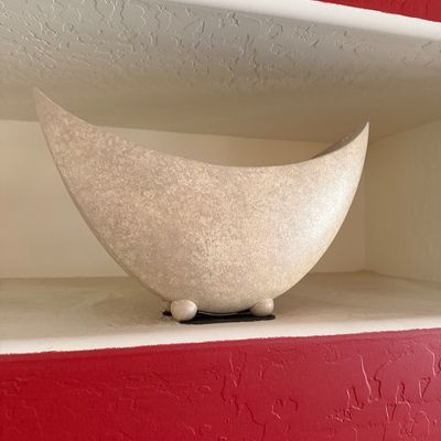 Sale Photo Thumbnail #284: Mid-century modern style crescent-shaped ceramic vessel with a textured beige finish, resting on small ball feet.