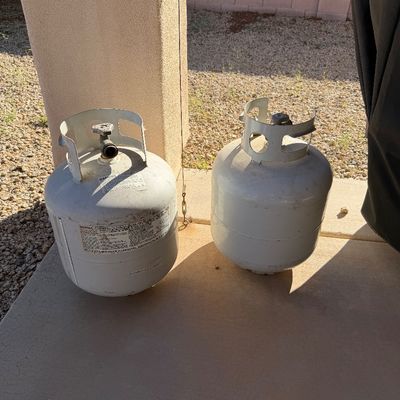 Sale Photo Thumbnail #238: Two standard 20-pound propane tanks with OPD valves, showing some exterior wear and scuffs.