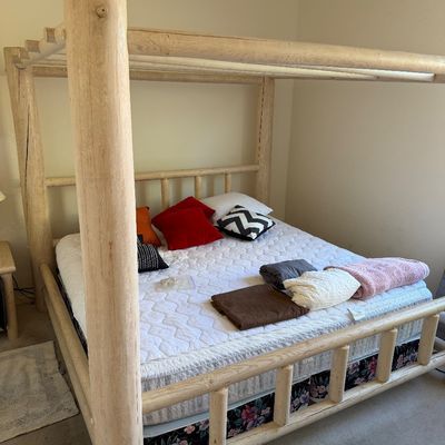Sale Photo Thumbnail #192: Rustic log canopy bed frame crafted from light-colored natural wood, featuring thick log posts and a matching headboard and footboard.