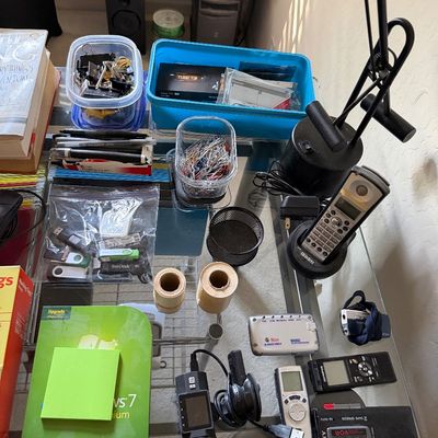 Assorted office supplies and electronics, including a Uniden cordless phone, a Sony microcassette recorder, digital voice recorders, USB...