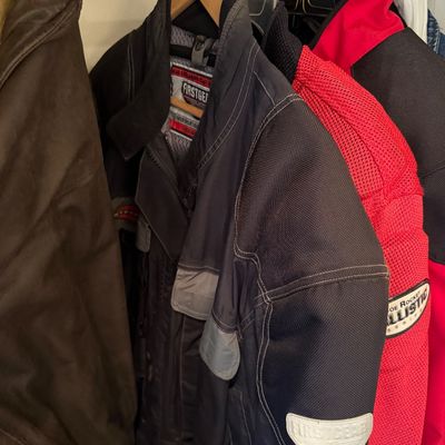 Sale Photo Thumbnail #180: Selection of men's motorcycle jackets hanging in a closet, including a black Firstgear jacket and a red and black Joe Rocket Ballistic Series jacket.