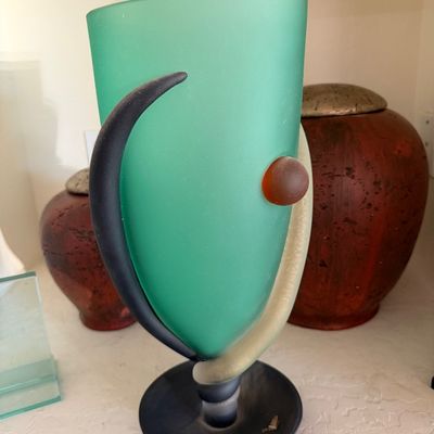 Sale Photo Thumbnail #272: Postmodern frosted art glass vase in green, black, and cream with a raised amber glass accent, displayed alongside ceramic vessels.