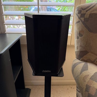 Sale Photo Thumbnail #312: Definitive Technology bipolar surround speaker mounted on a black metal floor stand.