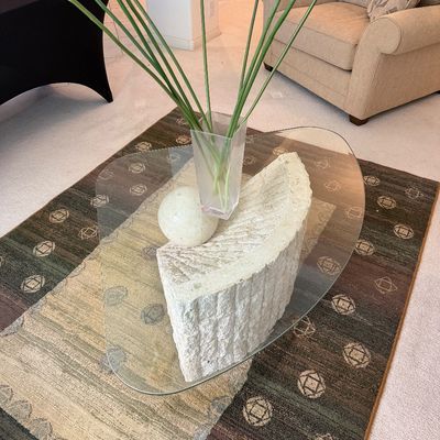 Sale Photo Thumbnail #305: Postmodern coffee table featuring a freeform glass top supported by a textured, semi-circular stone base and a spherical stone accent.