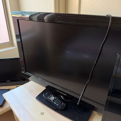 Sale Photo Thumbnail #185: Sharp Aquos flat-screen television with a black bezel and matching remote control, displayed on a light wood dresser.